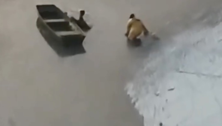Uomo cammina sul lago ghiacciato per raggiungere il cane