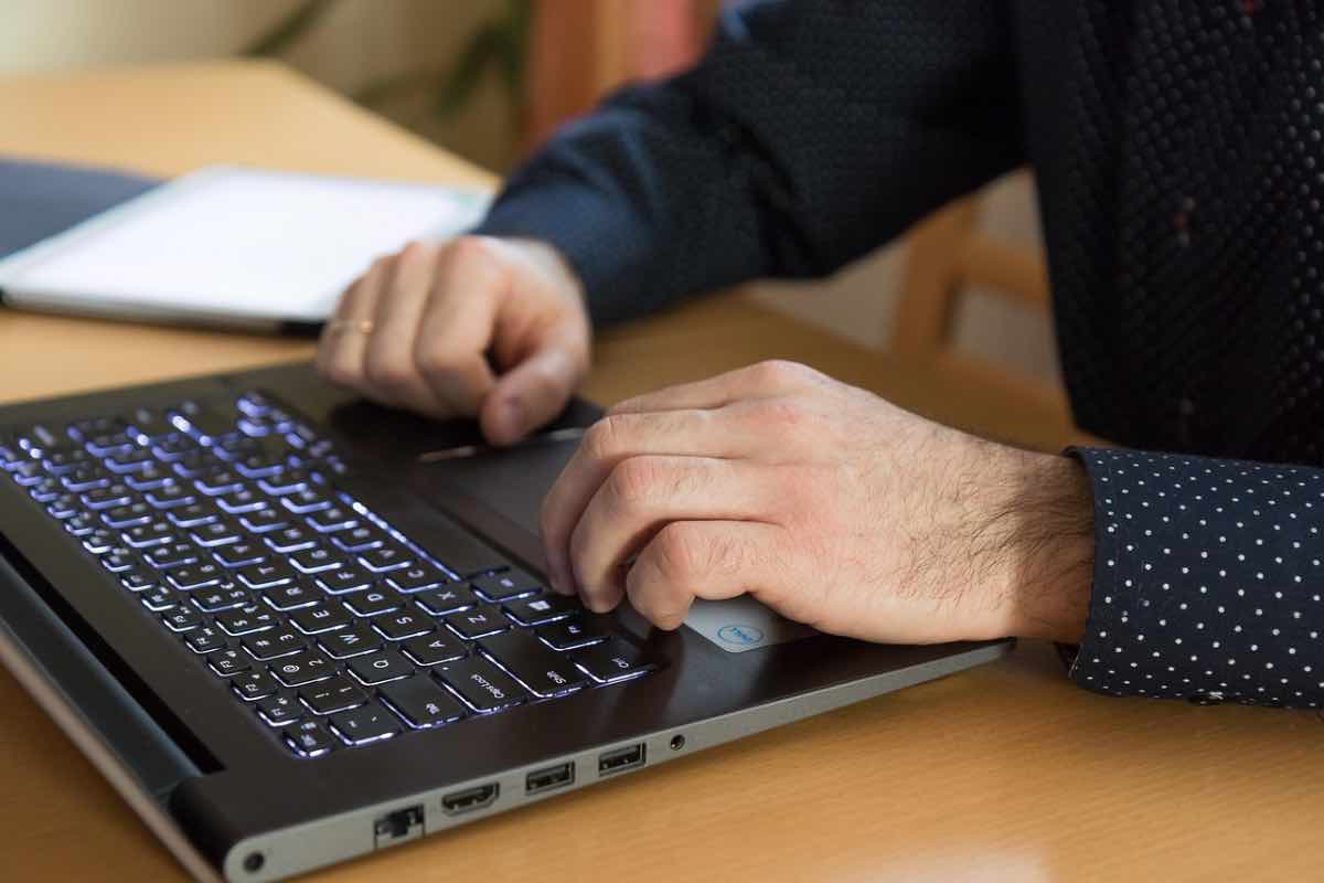 Uomo alla scrivania digita i tasti del computer